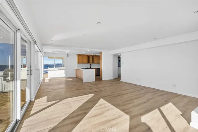 a large white kitchen with a refrigerator a stove top oven and a large window with wooden floor