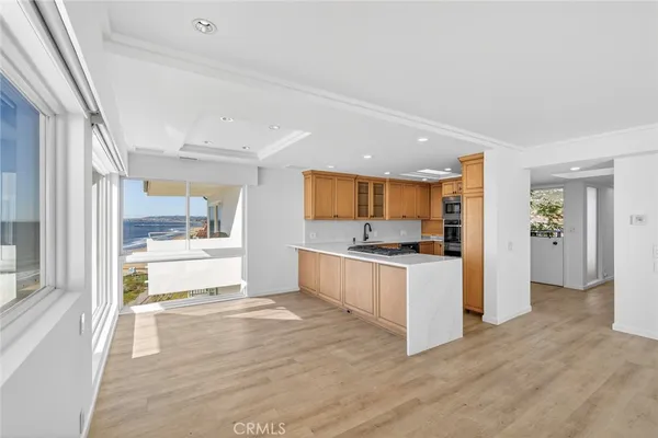 a large white kitchen with a refrigerator a stove top oven and a large window with wooden floor