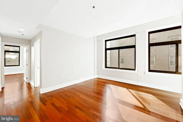 a view of an empty room with wooden floor and a window