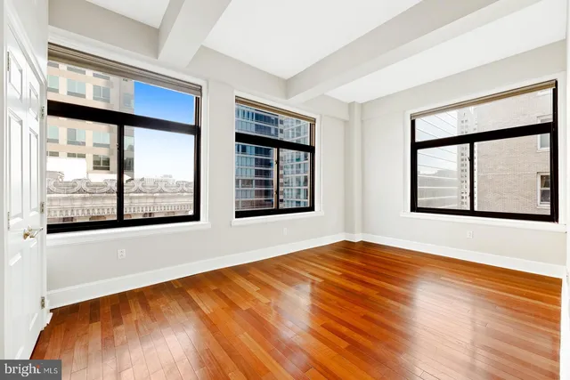 a view of empty room with wooden floor and white walls