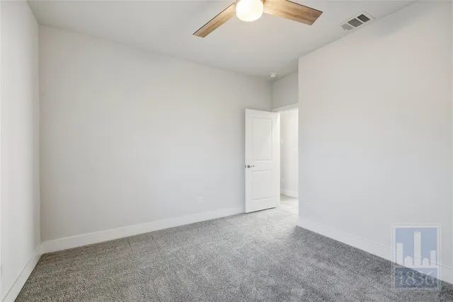 an empty room with a ceiling fan and carpet