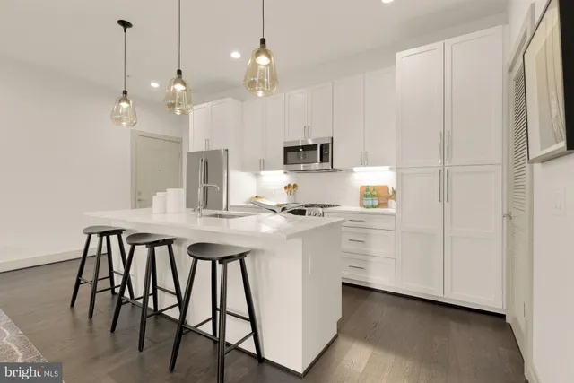 a kitchen with kitchen island a wooden floor and white appliances