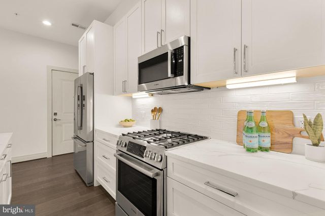 a kitchen with stainless steel appliances kitchen island a stove and a refrigerator with wooden floor