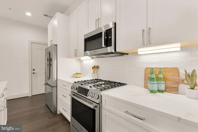 a kitchen with stainless steel appliances kitchen island a stove and a refrigerator with wooden floor