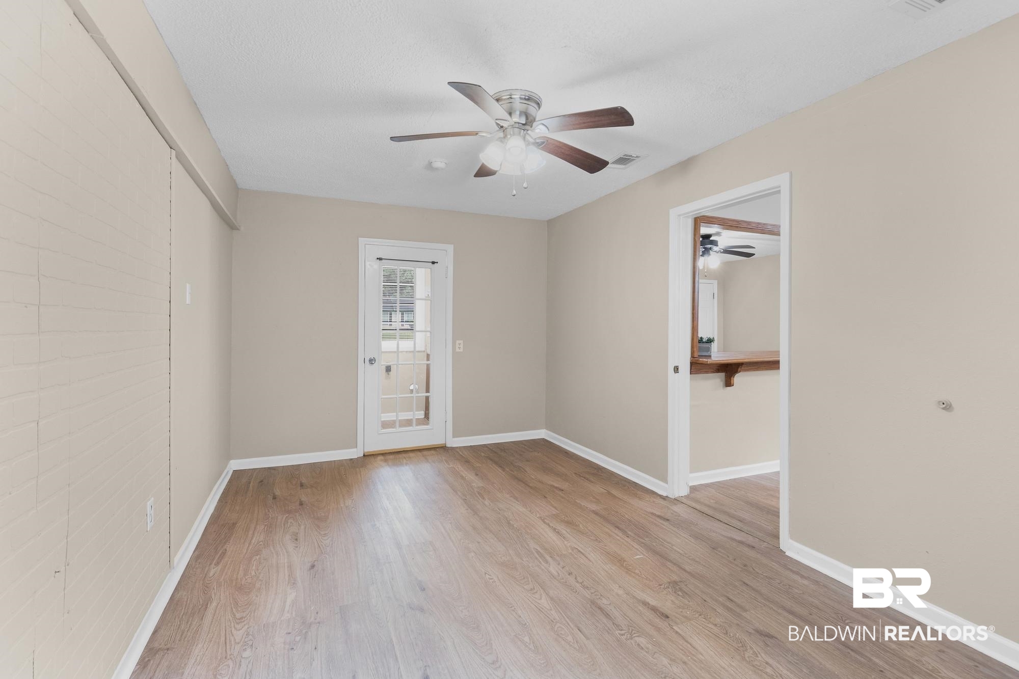 1560 Military Road Mount Vernon, AL 36560 - Photo 15 of 26 Open-concept room featuring wood-finish flooring, a ceiling fan with integrated lighting, and a white paneled door with glass inserts