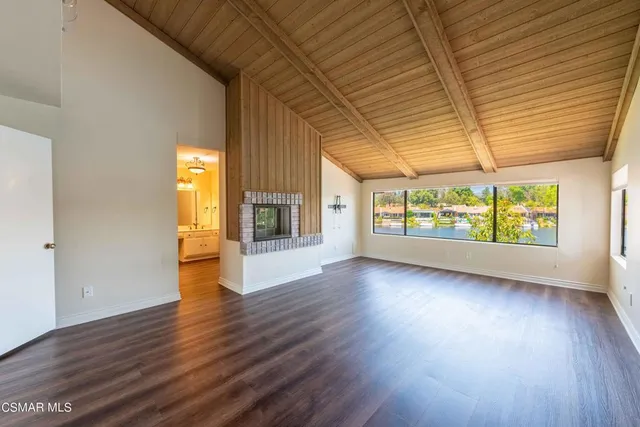 an empty room with wooden floor fireplace and windows