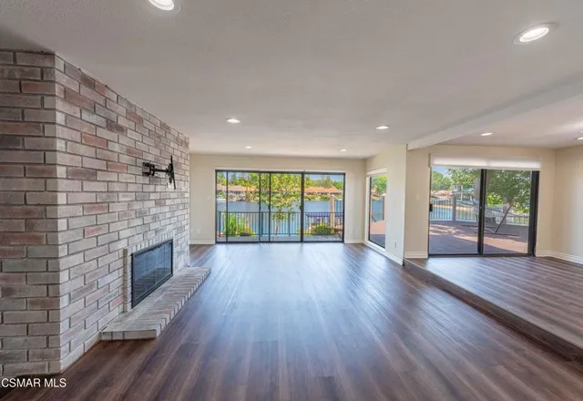 a view of an empty room with wooden floor and a fireplace