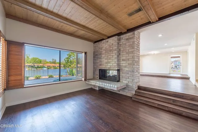 a view of wooden floor fire place and windows in an empty room