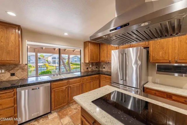 a kitchen with stainless steel appliances granite countertop a sink a stove and a refrigerator