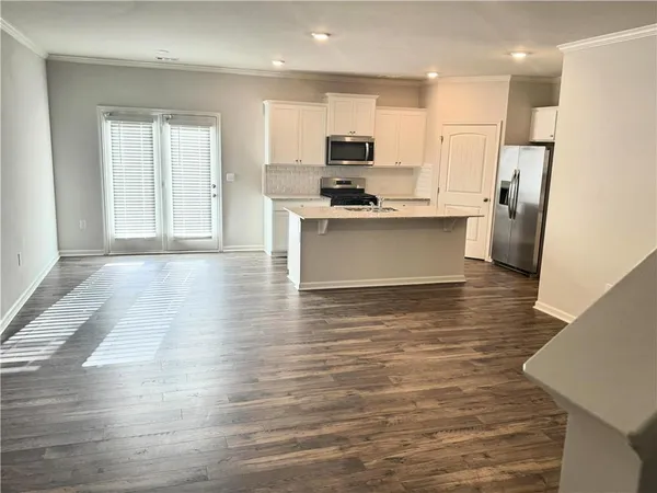 a large kitchen with stainless steel appliances wooden floor and a refrigerator