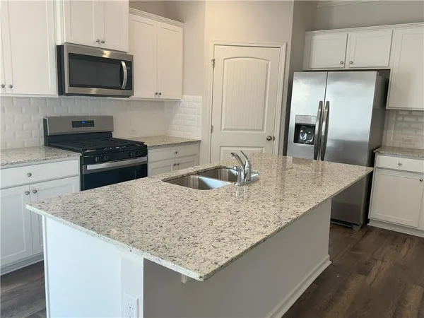 a kitchen with stainless steel appliances granite countertop a sink stove and refrigerator
