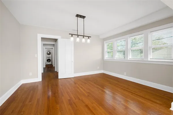 a view of an empty room with wooden floor fireplace and a window