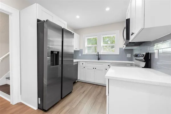 a kitchen with stainless steel appliances a refrigerator sink and wooden floor