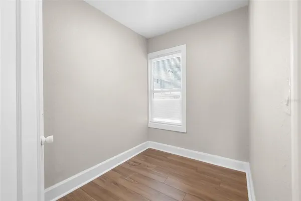 a view of an empty room with wooden floor and a window