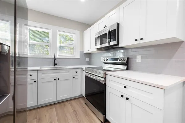 a kitchen with stainless steel appliances white cabinets a sink and a stove