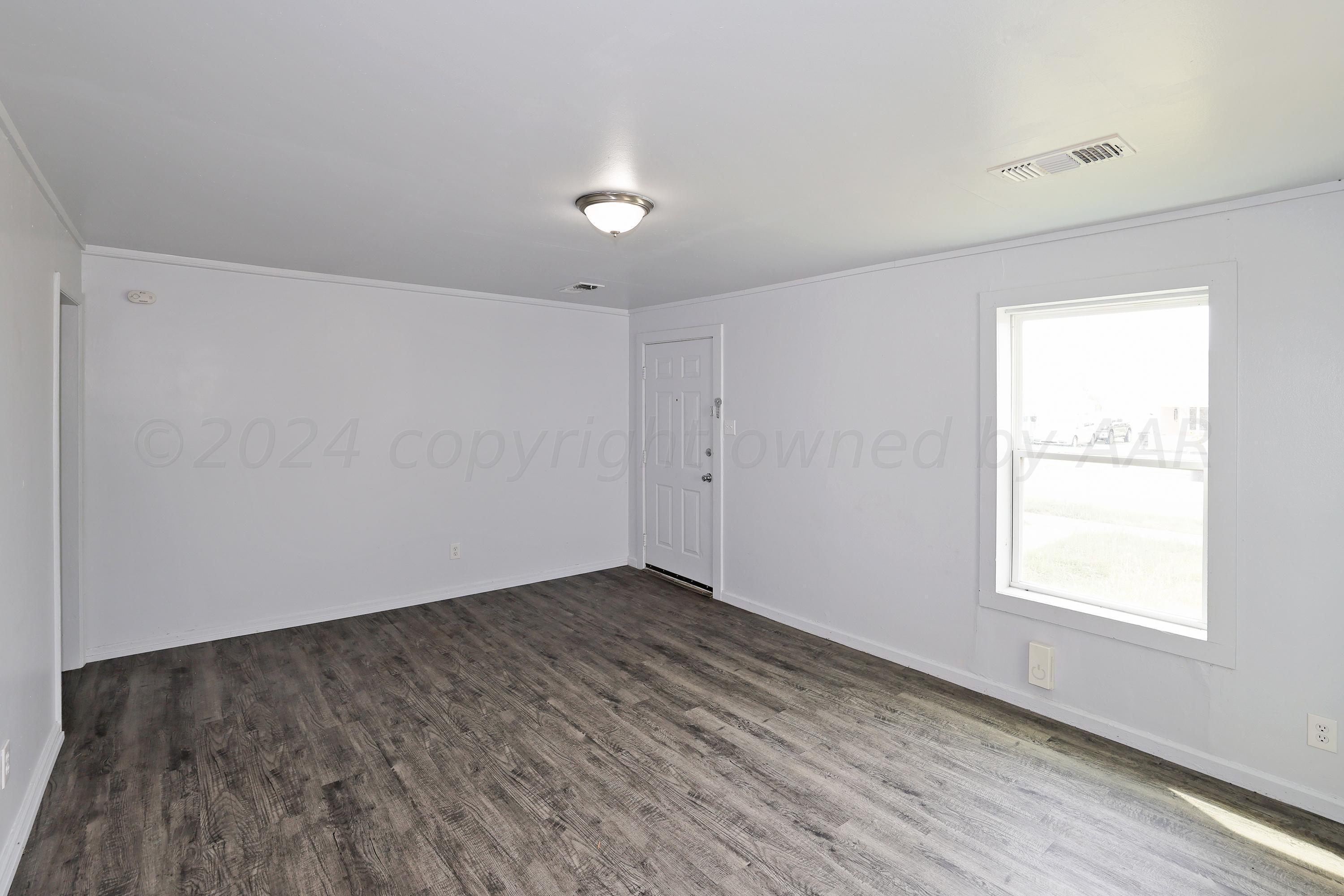 3703 South Monroe Street Amarillo, TX 79110 - Photo 5 of 14 an empty room with wooden floor and windows