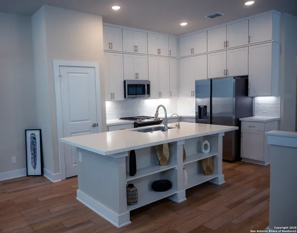 a kitchen with kitchen island stainless steel appliances a sink and refrigerator