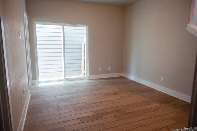 a view of empty room with wooden floor and fan