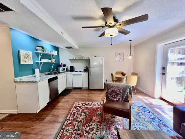 a living room with furniture kitchen view and a wooden floor