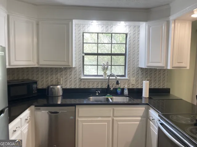 a kitchen with granite countertop a sink stove and cabinets