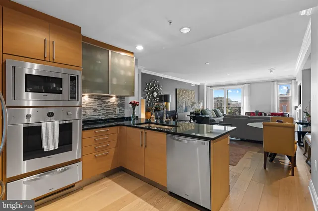 a kitchen with a sink stainless steel appliances wooden floor and cabinets