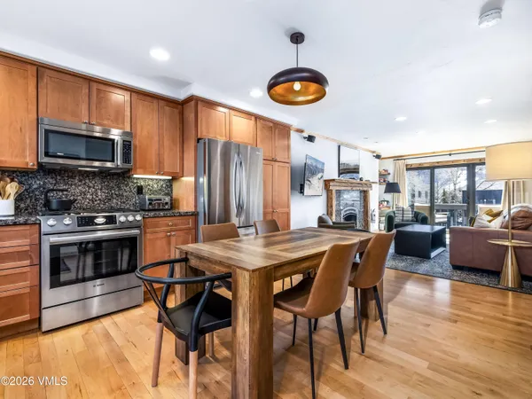 a kitchen with stainless steel appliances wooden floor dining table and chairs