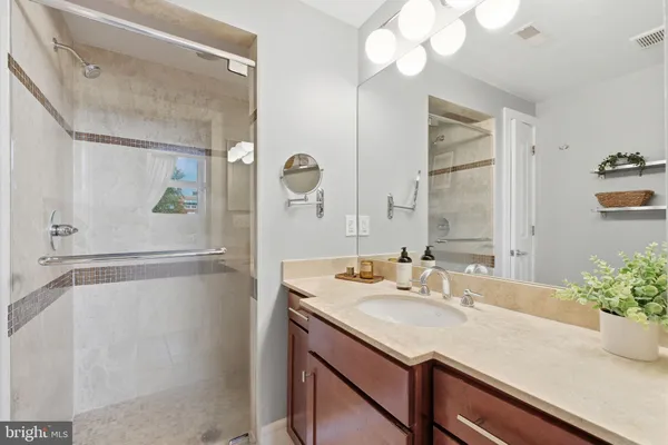 a bathroom with a granite countertop sink a mirror and a shower