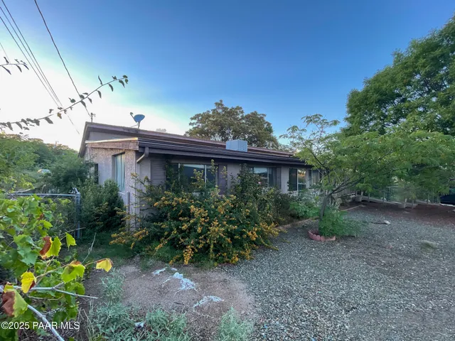 a view of a house with a yard plants and large tree