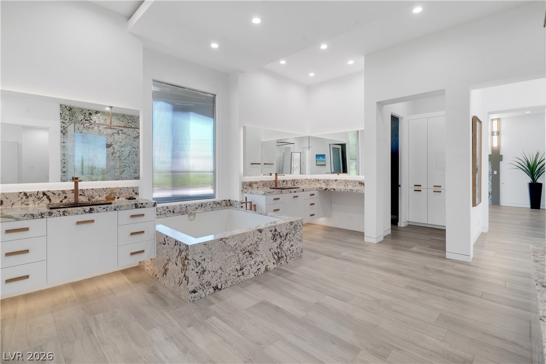 10 Ridge Blossom Road Las Vegas, NV 89135 - Photo 21 of 64 Full bathroom featuring two vanities, a garden tub, a stall shower, light wood-style flooring, and recessed lighting