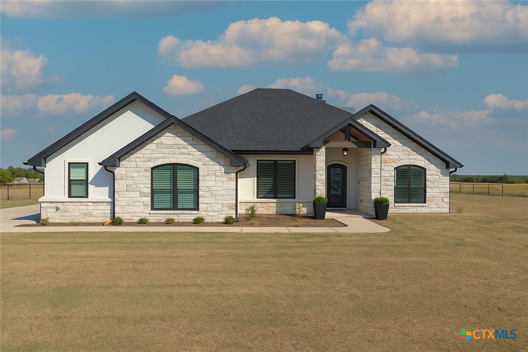 a view of white house with a yard and potted plants
