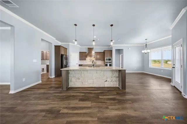 a large kitchen with stainless steel appliances granite countertop a lot of counter space and wooden floor