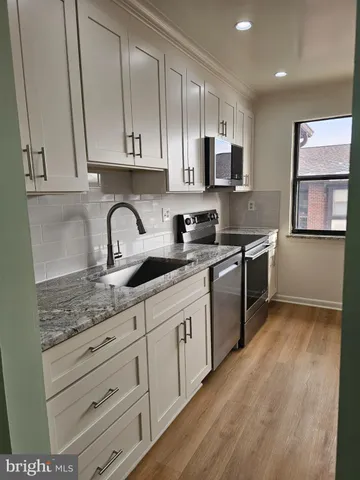 a kitchen with granite countertop a sink stainless steel appliances and cabinets