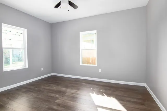 an empty room with wooden floor and windows