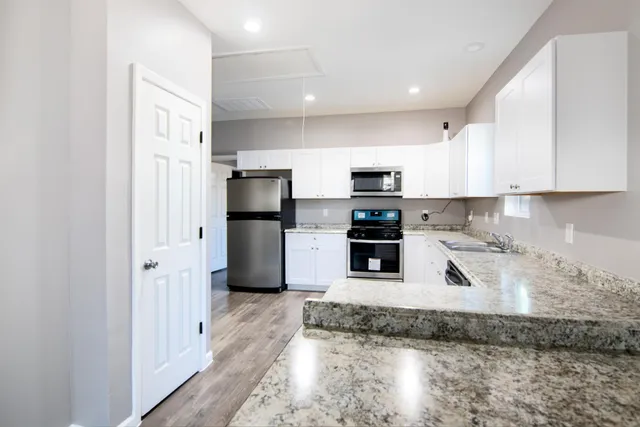 a kitchen with stainless steel appliances granite countertop a refrigerator a stove and a sink