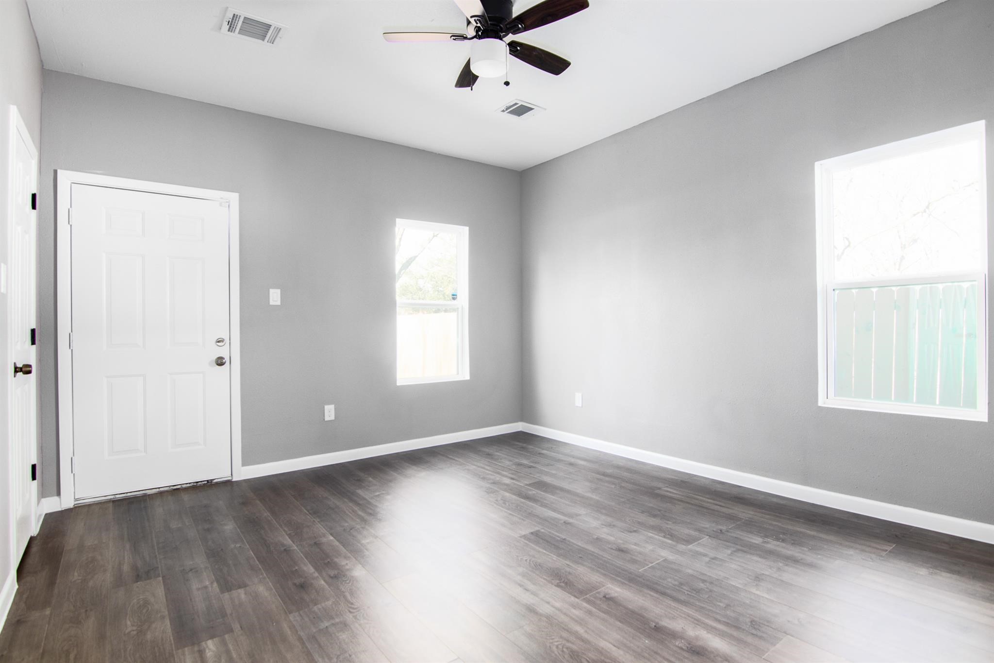1709 Stevens Street Houston, TX 77026 - Photo 8 of 17 an empty room with wooden floor chandelier fan and windows