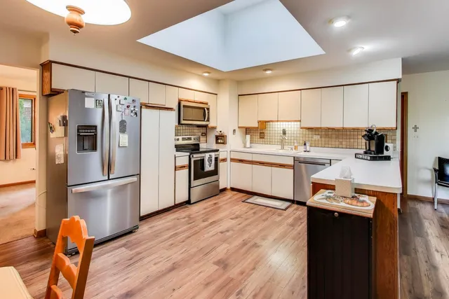 a kitchen with stainless steel appliances a refrigerator sink and wooden floor