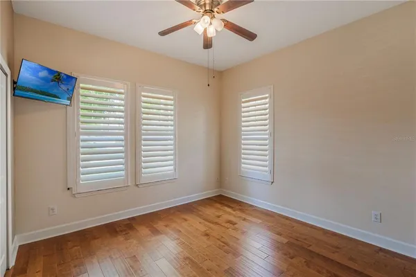an empty room with windows and ceiling fan