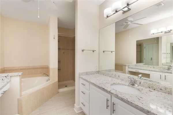 a bathroom with a granite countertop sink a bathtub and a mirror