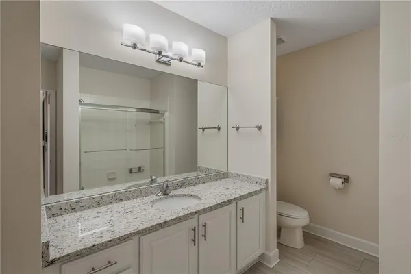 a bathroom with a granite countertop sink toilet and shower