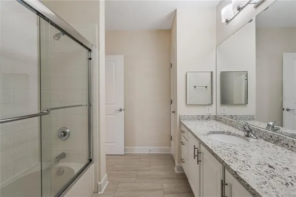 a bathroom with a granite countertop sink a mirror and a bathtub