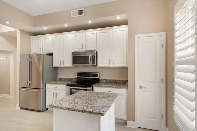 a kitchen with stainless steel appliances granite countertop a refrigerator and a stove top oven