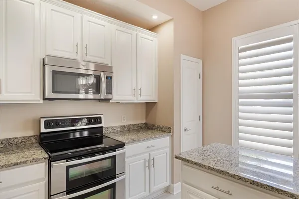 a kitchen with granite countertop white cabinets and appliances