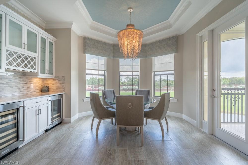 16444 Carrara Way, Unit 7301 Naples, FL 34110 - Photo 14 of 42 a dining room with wooden floor a chandelier a glass table and chairs