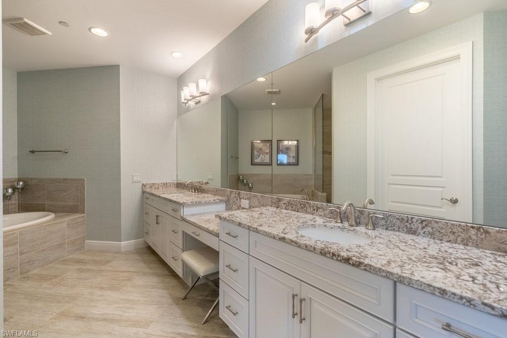 16444 Carrara Way, Unit 7301 Naples, FL 34110 - Photo 17 of 42 a bathroom with a granite countertop sink large mirror and a