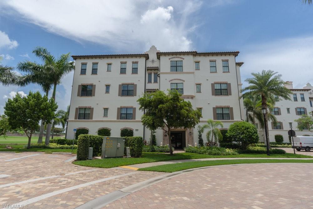16444 Carrara Way, Unit 7301 Naples, FL 34110 - Photo 32 of 42 a view of a building with a yard and large trees