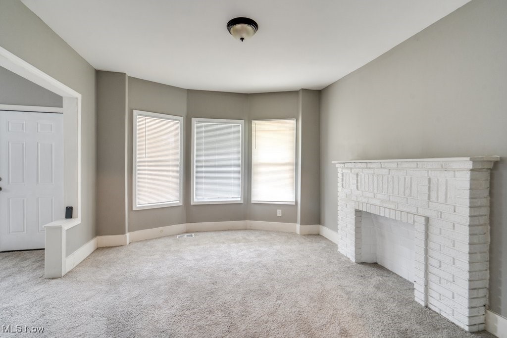 1261 Rozelle Avenue Cleveland, OH 44112 - Photo 8 of 32 Unfurnished living room featuring a brick fireplace and carpet