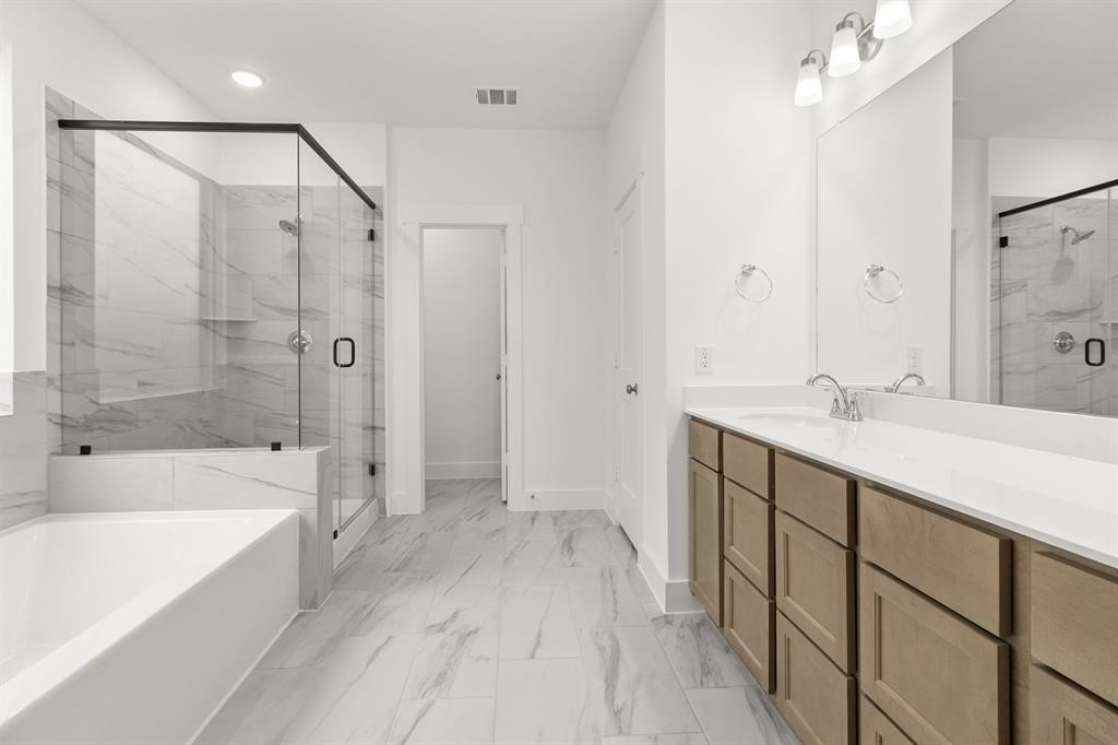 8239 Red Shiner Way Fulshear, TX 77441 - Photo 6 of 25 a spacious bathroom with a double vanity sink a mirror and a bathtub