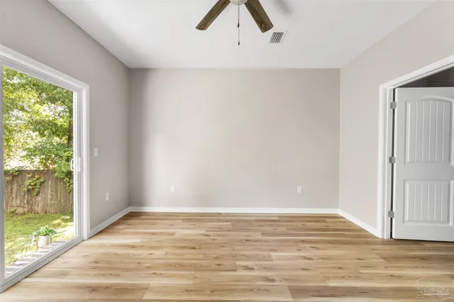 a view of an empty room with window and wooden floor