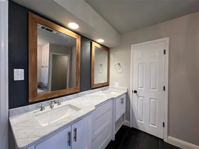 a spacious bathroom with a granite countertop sink and a mirror
