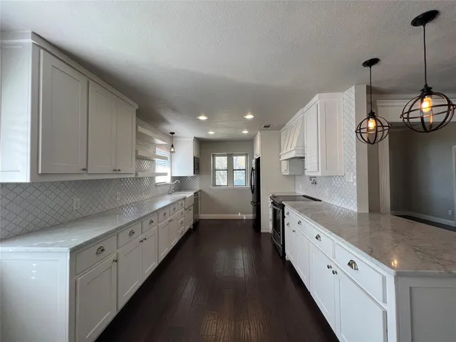 a large kitchen with stainless steel appliances lots of counter space and wooden floor